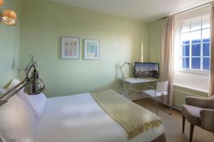 Schlafzimmer mit einem Bett, einem Schreibtisch und einem TV in der Unterkunft Brueghel in Lille