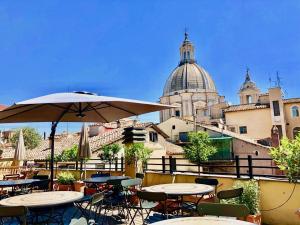 eine Terrasse mit Tischen, Stühlen und einem Sonnenschirm in der Unterkunft Navona Residenza de Charme in Rom