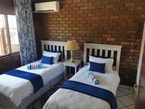 two beds in a room with a brick wall at The Dunes in St Lucia