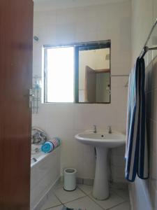 a bathroom with a sink and a mirror and a tub at The Dunes in St Lucia