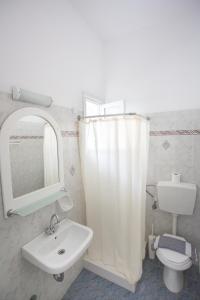 W łazience znajduje się umywalka, toaleta i lustro. w obiekcie Louiza Hotel w mieście Parikia