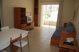een woonkamer met een bank, een tafel en een tv bij Flat Serra in Rio Quente