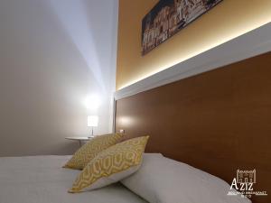 uma cama com almofadas amarelas e brancas num quarto em Aziz b&b em Palermo