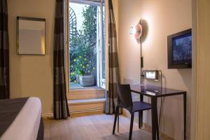 a hotel room with a desk and a window at Tilsitt Etoile Paris in Paris