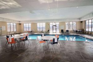 una piscina con mesas y sillas en un edificio en Days Inn & Suites by Wyndham La Crosse-Onalaska, en Onalaska