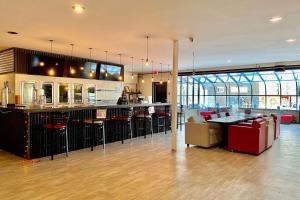 un restaurante con un bar con mesas y sillas en Ramada by Wyndham Whitecourt, en Whitecourt