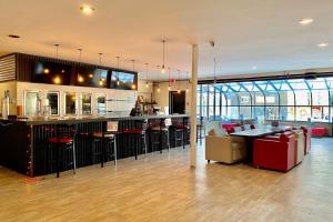 a restaurant with a bar with chairs and tables at Ramada by Wyndham Whitecourt in Whitecourt