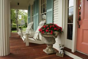 a porch with rocking chairs and a vase of flowers at Captain Farris House in South Yarmouth