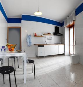uma cozinha com uma mesa branca e cadeiras pretas em B&B Business em Casalnuovo di Napoli