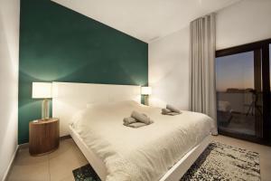 a bedroom with a white bed with a green wall at Modern Villa close to Costabella beach in Marbella