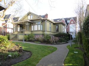 a yellow house with a walkway in a yard at Robert Porter House Inn in Victoria