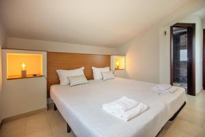 a bedroom with a white bed with two towels on it at Villa Rafaella II Palace by Atlantic Places in Albufeira +37 photos