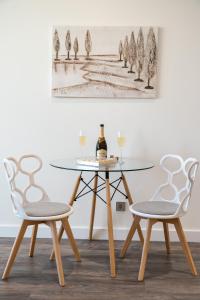 una mesa de cristal con 2 sillas y una mesa con una botella de vino en VICTORY-21 LUXURY APARTMENT CEnTER, en Kiev