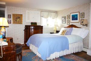 a bedroom with a large bed with a blue blanket at The White House Inn in Cooperstown