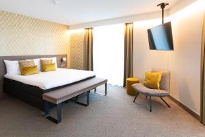 
a room with a bed, chair, table and a lamp at Van der Valk Hotel Groningen-Hoogkerk in Groningen
