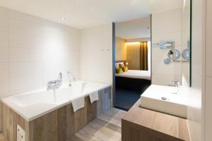 
a bathroom with a tub, sink, and mirror at Van der Valk Hotel Groningen-Hoogkerk in Groningen
