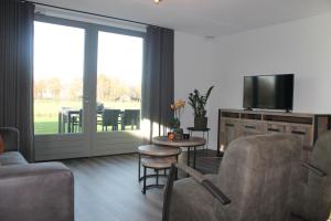 a living room with a couch and chairs and a television at De Pan in Hapert