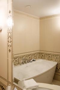 a bathroom with a bath tub, sink and mirror at Dvor Podznoeva Glavniy Korpus in Pskov