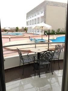 a table and chairs with an umbrella on a balcony at 2nd Cecilia beach resort studio in Hurghada