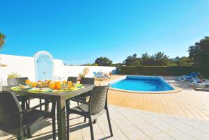einen Esstisch und Stühle neben einem Pool in der Unterkunft Villa Martinica by Algarve Vacation in Guia