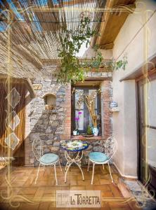 un patio con mesa, sillas y pared de piedra. en B&B La Torretta, en Maratea
