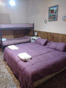 un grande letto viola con asciugamani sopra di El Indio - Casa de campo a Villa del Salvador