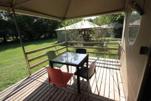 a patio with a table and chairs on a deck at Camping L'îlot du Chail in Sansais +37 photos
