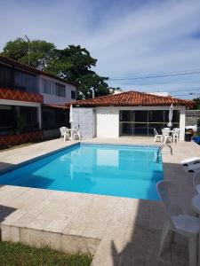 einen Pool mit Stühlen und ein Haus in der Unterkunft Casa 4/4(Amplos), Cond. fechado com piscina-150m2 in Salvador