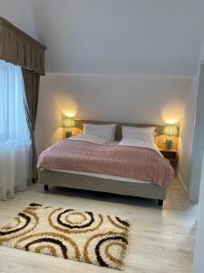 a bedroom with a bed with two lamps and a rug at ApartamentS in Râşnov