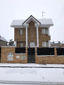 una casa con una valla en la nieve en Chalé Barajas Escala, en Madrid