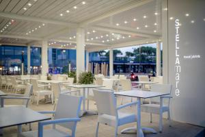 a restaurant with tables and white chairs and lights at Stellamare in Caorle