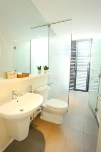 a white bathroom with a toilet and a sink at Oceanami Resort in Long Hai