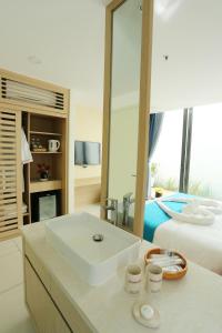 uma casa de banho branca com um lavatório e uma cama em Oceanami Resort em Long Hai