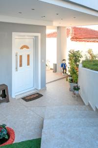 una porta bianca di una casa con piante di Loridis View Apartments a Prinos