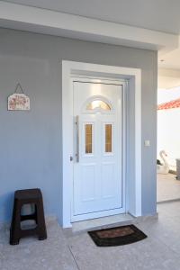 una puerta blanca en una pared azul con un taburete en Loridis View Apartments en Prínos