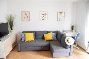 a living room with a gray couch and yellow pillows at The Wind's Breath, perfect for relaxing getaway in La Oliva