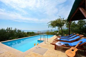 - une piscine avec des chaises longues et une guitare dans l'établissement Holiday Home Nevenka, à Kaštela