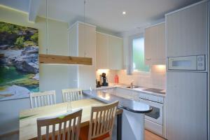 a kitchen with white cabinets and a wooden table and chairs at La Campagnola - Top Swiss Family Hotel in San Nazzaro