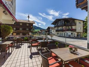 a patio with tables and chairs and a view of a street at Pension Elisabeth in Westendorf