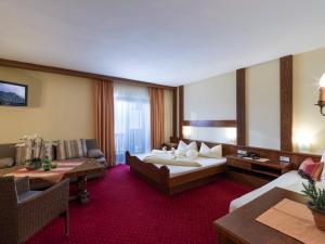 ein Hotelzimmer mit einem großen Bett und einer Couch in der Unterkunft Pension Elisabeth in Westendorf