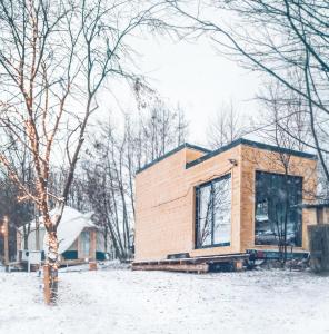 een klein huisje in de sneeuw met een boom bij LushHills - Tiny House - Modern House On Wheels in Regulice