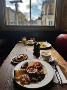 a wooden table with plates of breakfast food on it at The Crooked Swan in Crewkerne