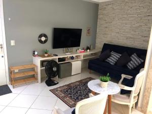 a living room with a blue couch and a tv at MARCOLINI - Praia Rio - Barra da Tijuca in Rio de Janeiro