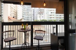 een balkon met 2 stoelen en een tafel met wijnglazen bij The Royal 213 - Downtown República - Centro - SP in Sao Paulo