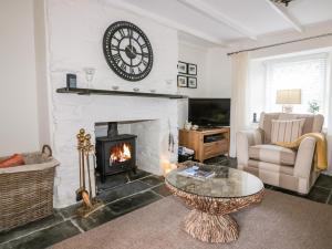 a living room with a fireplace with a clock on the wall at Hawthorn Cottage in Bodmin