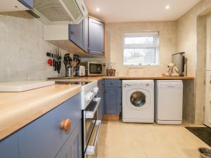 a kitchen with blue cabinets and a washer and dryer at Hawthorn Cottage in Bodmin