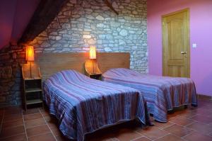 a bedroom with two beds and a stone wall at Gîtes Ferme de la Barrière in Chimay