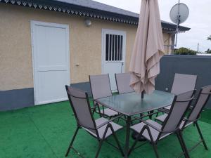 una mesa de cristal con sillas y una sombrilla en Chez kafrine et minous, en Ravine des Cabris