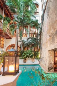 uma piscina no meio de um edifício com palmeiras em Hotel Casa San Agustin em Cartagena de Indias