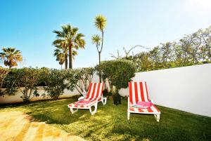 dos sillas rojas y blancas sentadas en el césped en Villa Mauritius by Algarve Vacation, en Albufeira